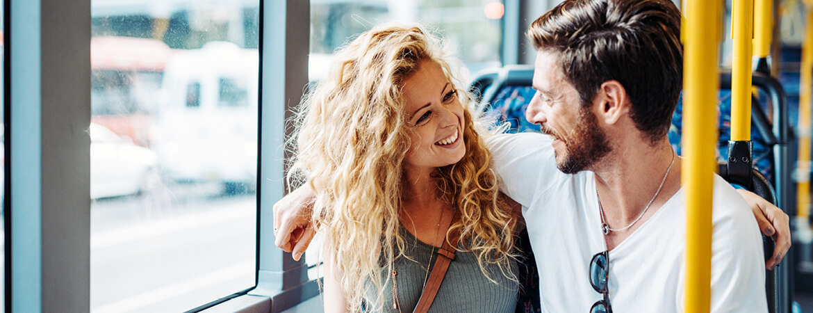 Woman and man smiling and looking at one another on a bus