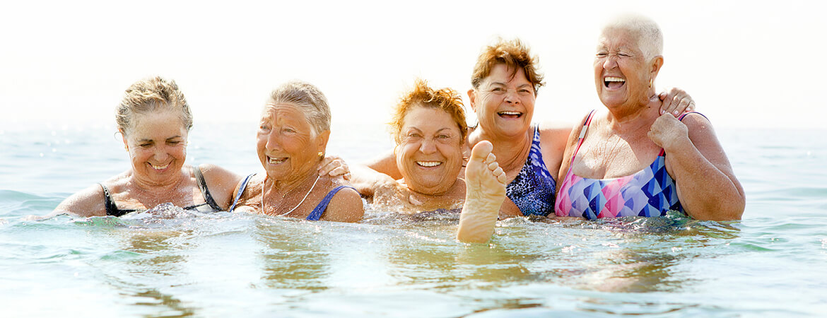 Group of women laughing together while in the water.
