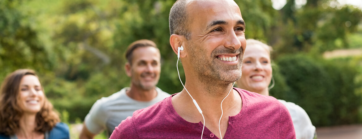 A group of friends exercising with man in the foreground listening to music through his headphones.