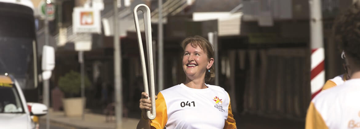 QSuper female member holding the Commonwealth Games Queen's Baton and smiling