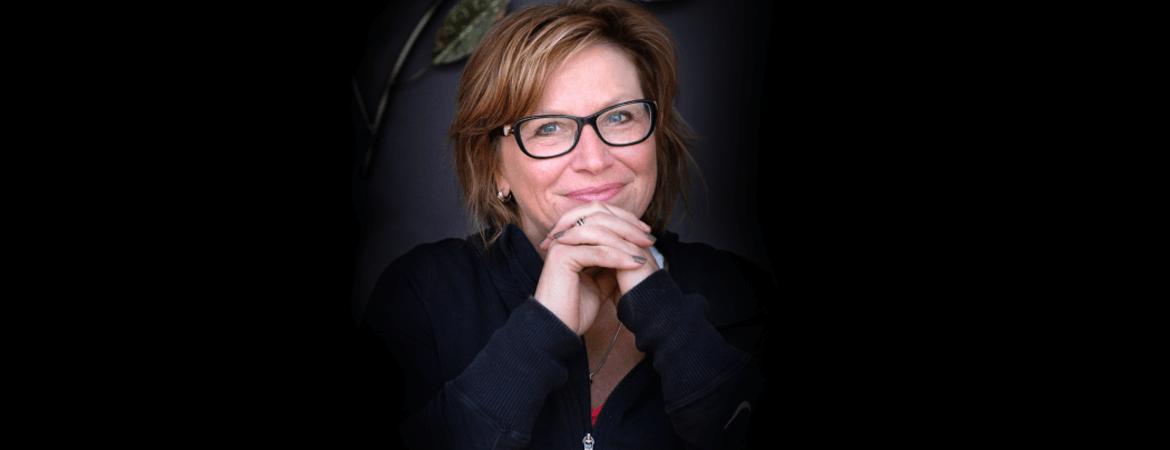 Rosie Batty wearing glasses leaning on her hands with fingers interlaced.