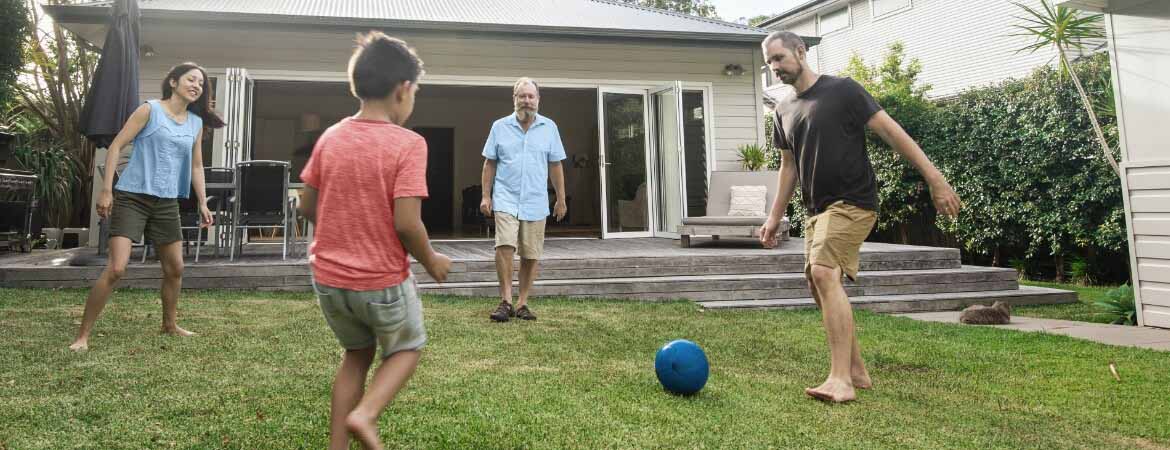 Family kicking a ball in the backyard