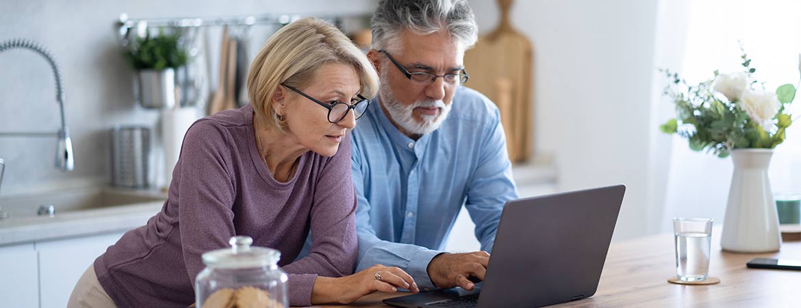 A-senior-couple-are-leaning-next-to-each-other-looking-at-a-laptop