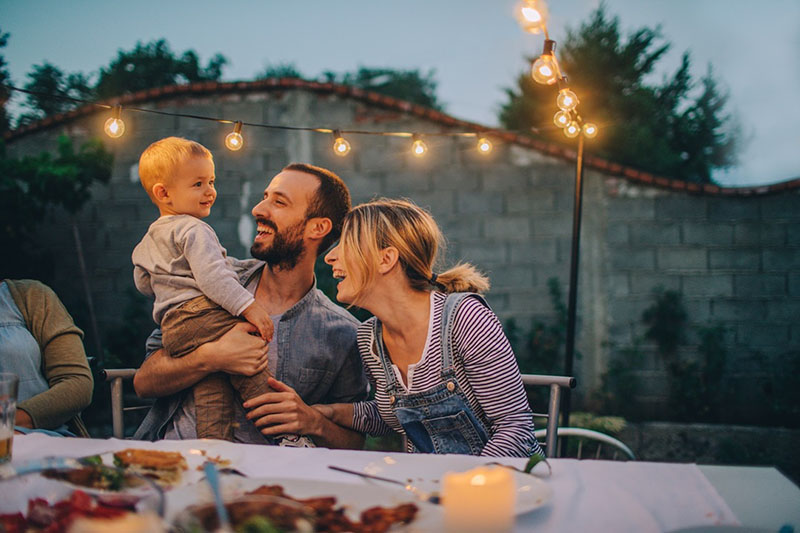 Smiling mother and father with baby at an outdoor barbeque