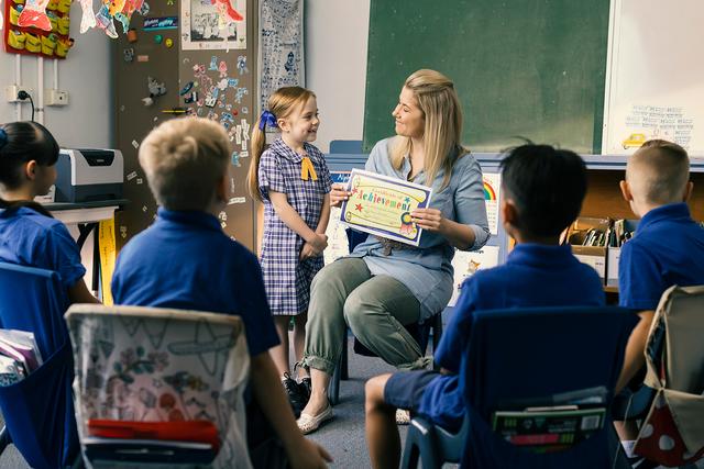 Young girl receiving a certificate from a teacher