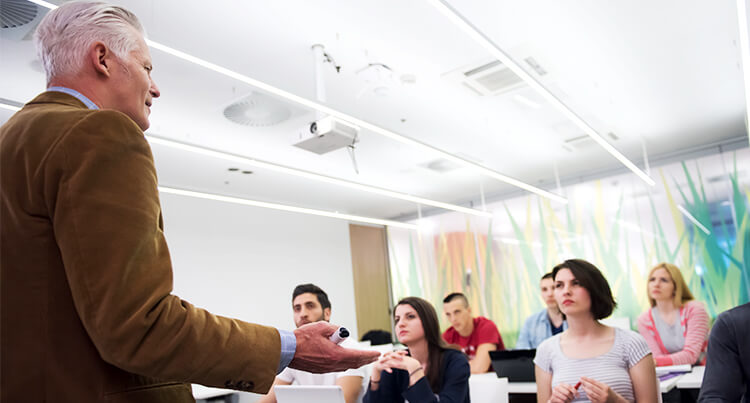Lecturer standing at the front of the classroom and teaching his students