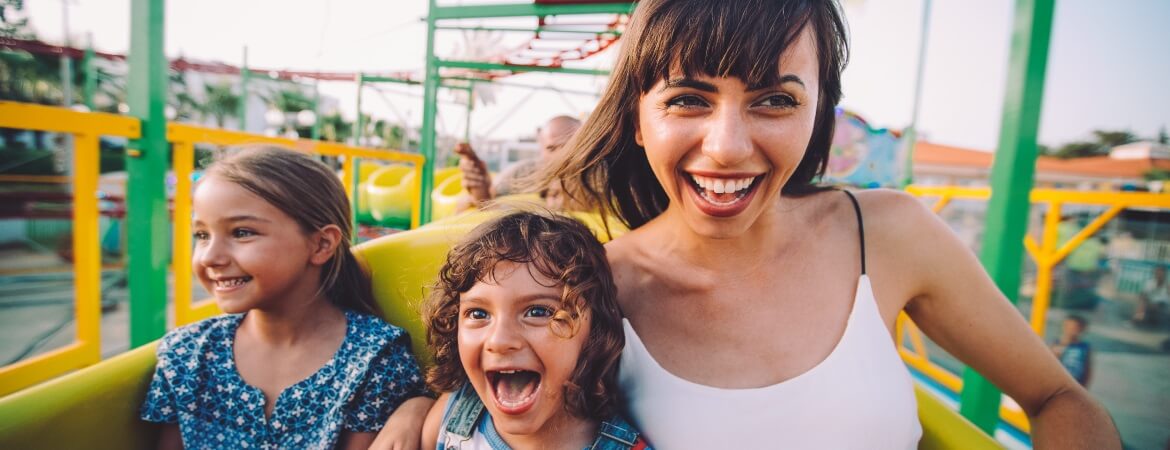 Mother and two children enjoying their rollercoaster ride together at a theme park.